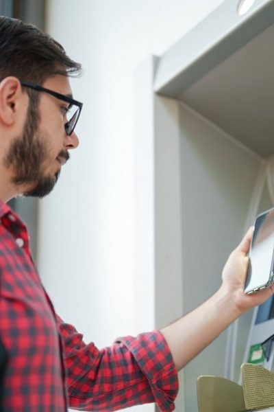 young-man-using-smart-phone-on-atm